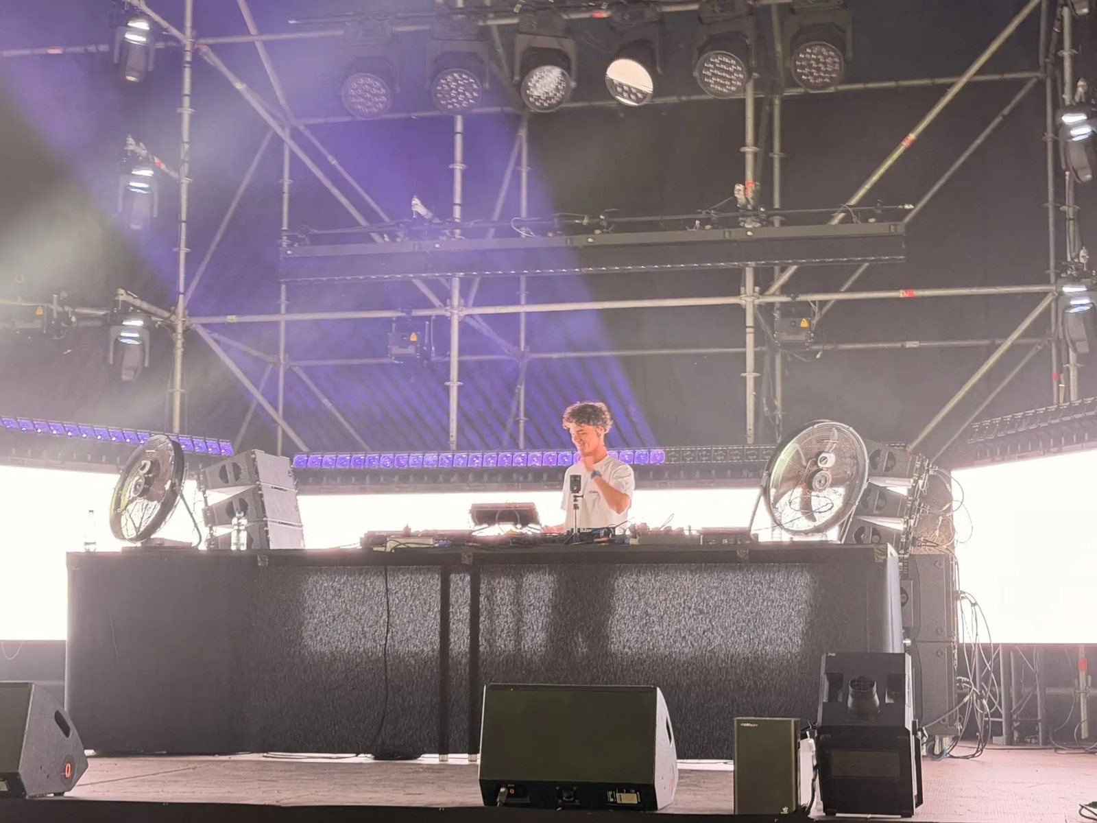 Festival stage in purple light with the DJ booth in the middle