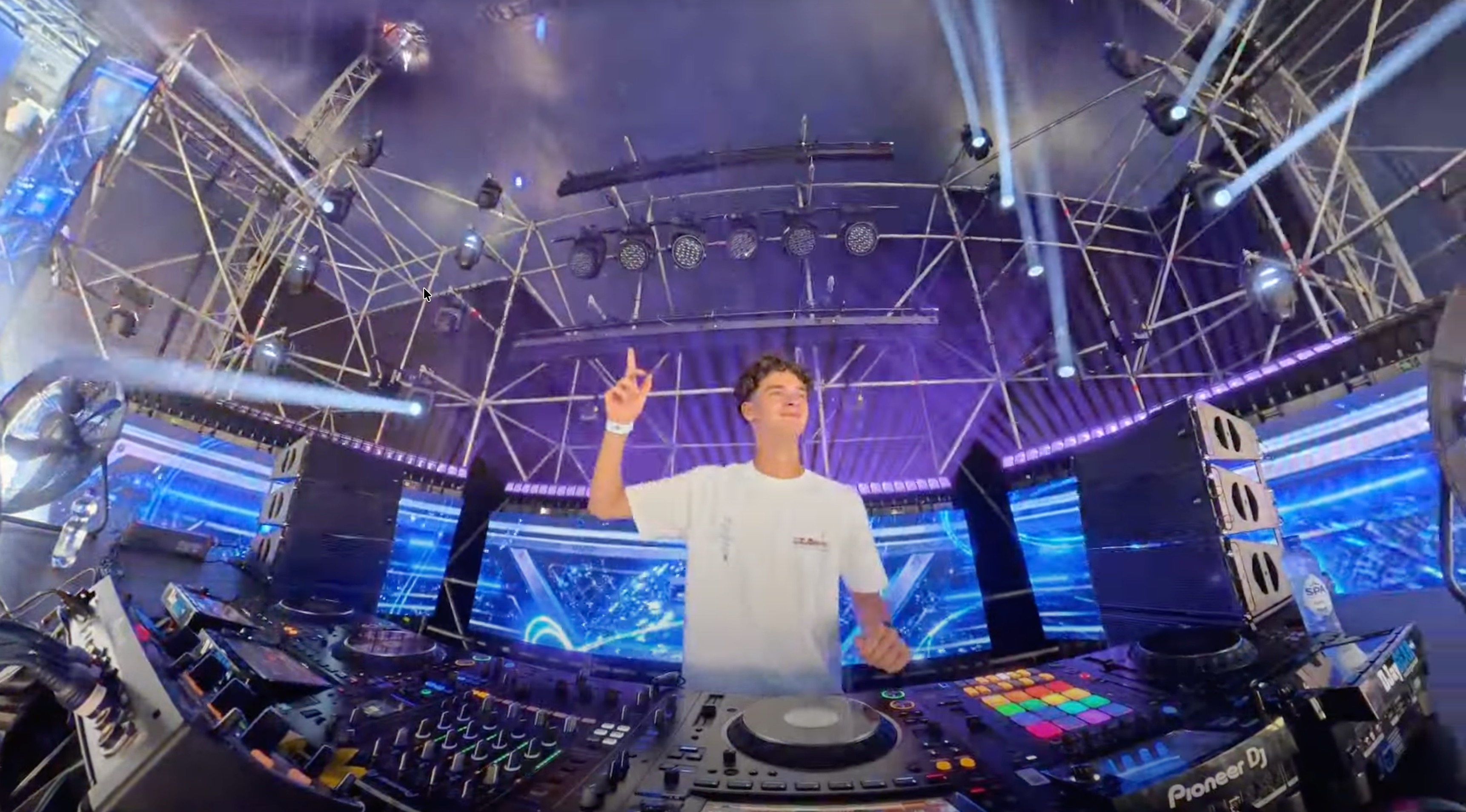 DJ Tuur with his hand in the air behind the Pioneer booth on the Park City Live stage