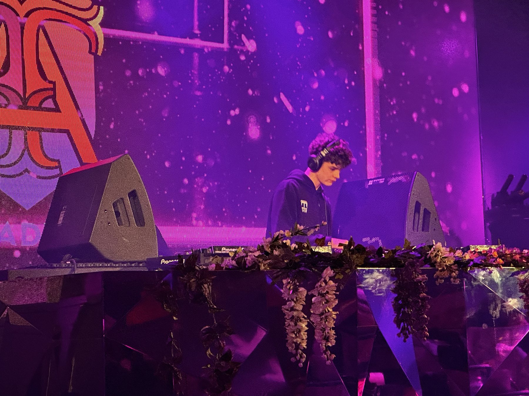 DJ Tuur behind the decks in a club lit in purple